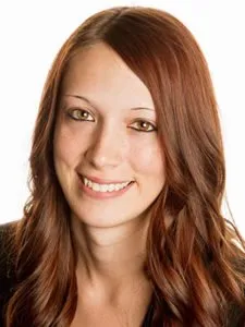 Portrait of a smiling woman with long auburn hair and light skin against a white background.